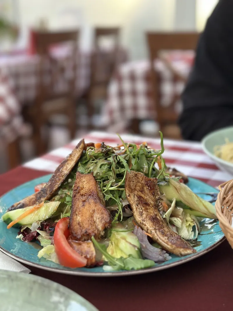 Insalata con Pollo mit gebratenen Hähnchenstreifen auf blauem Teller