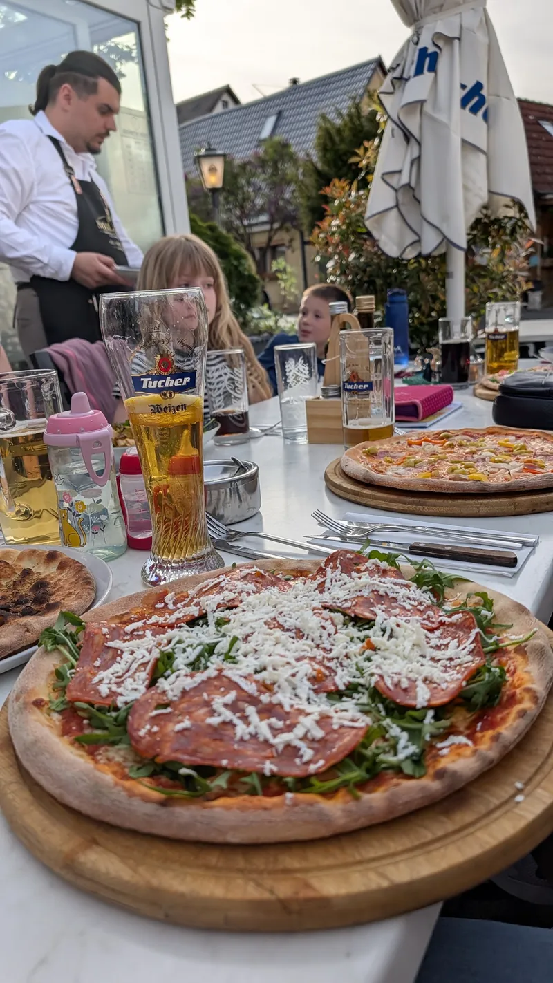 Pizza Milano mit Parmaschinken, Rucola und Parmesan auf dem Holzbrett