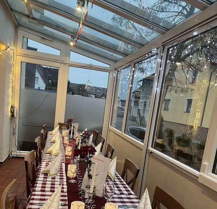 Lange festlich gedeckte Tafel im Wintergarten mit Kerzen und Blumen